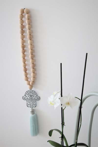Decorative Hamsa wall hanging with wood bead accents, featuring intricate patterns and a natural, rustic aesthetic, ideal for adding a touch of cultural charm and spiritual significance to your home decor