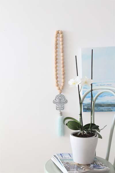 Beautifully crafted Hamsa wall hanging with natural wood bead embellishments, adding a touch of cultural elegance and spiritual significance to your home decor