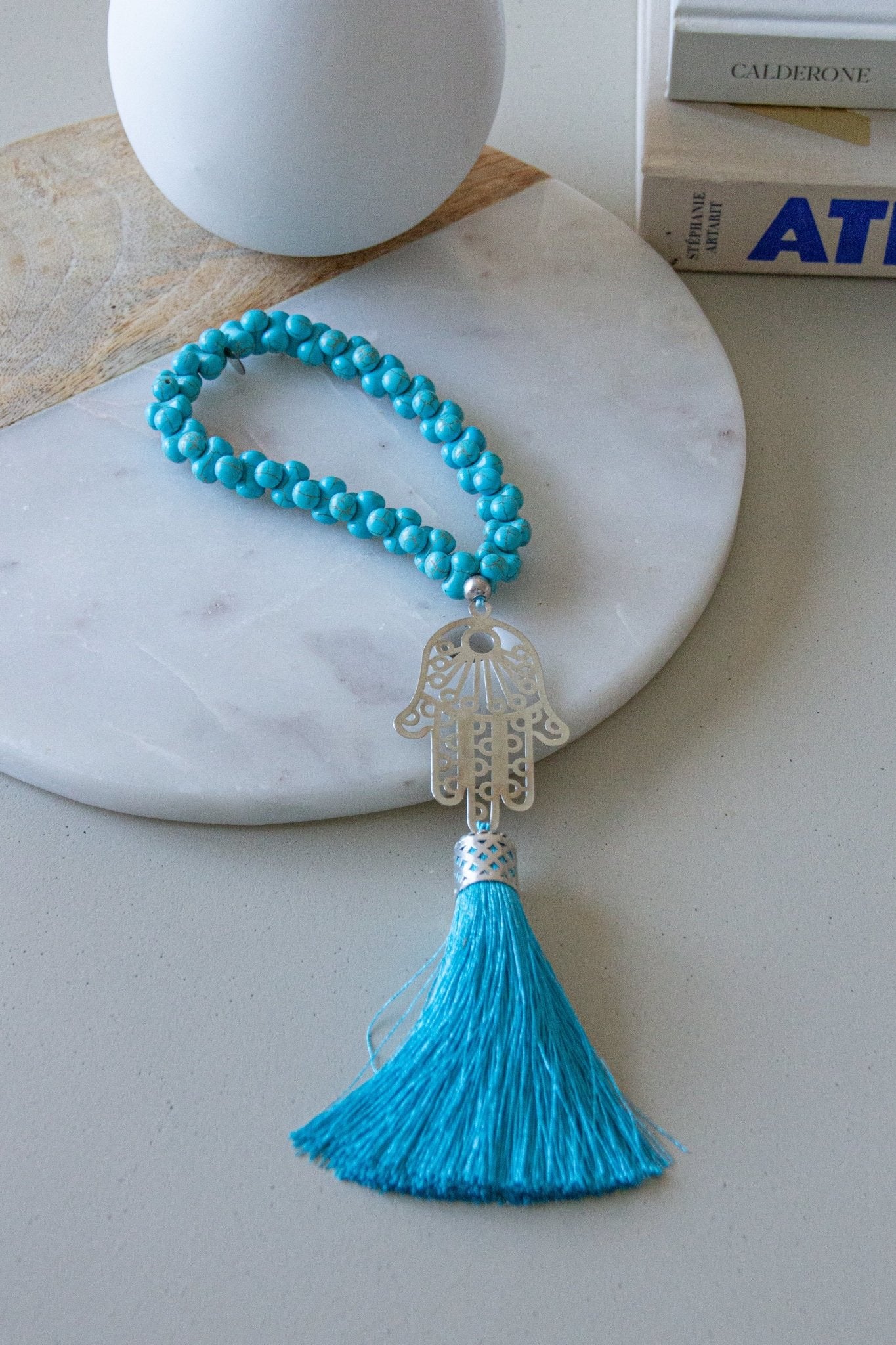 Silver-plated Hamsa hand wall hanging with turquoise Howlite stones and silk tassel. Modern bohemian protection charm against evil eye